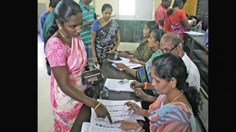 Poll officials at the R. K. Nagar Assembly constituency verify the electoral rolls on Sunday (Photo: DC)