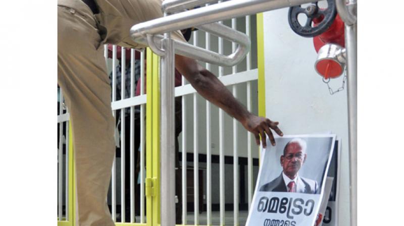 A police official places a poster on E. Sreedharan in a corner at a Kochi Metro station on Thursday. (Photo:  DC)