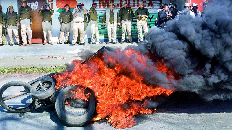 Police personnel look on as tyres are seen ablaze during a strike called by All Assam Students Union and the North East Students Organisation in protest against Citizenship (Amendment) Bill, 2016, in Dibrugarh.	PTI