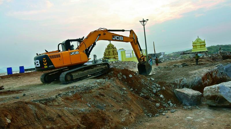 An earthmover works on the Yadadri hill with the Lakshmi Narasimha Swamy temple in the backdrop. Below: Progress on the approach roads (PhotoGandhi)