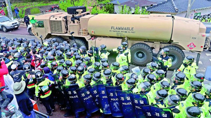 Protesters and police stand by as trailers carrying the THAAD missile defence equipment enter a deployment site in Seongju on Wednesday. (Photo: AFP)