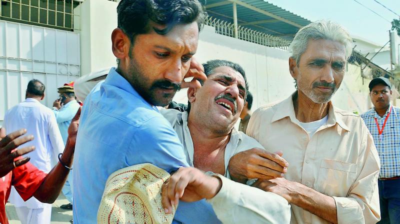 People comfort a family member of a police officer killed during a shootout at the Chinese Consulate in Karachi on Friday.  (Photo:AP)
