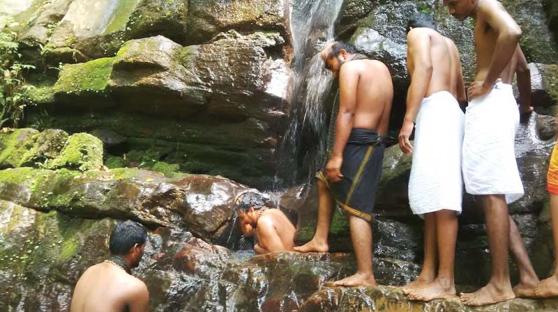 A pilgrim sits inside the pit or uralkuzhi at the waterfall. 	(Photo: DC)