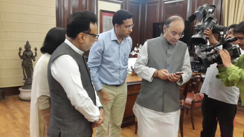 Revenue Secretary Hasmukh Adhia looks on while Finance Ministry Arun Jaitley browses through GST Rates Finder mobile app. (Photo: Finance Ministry)
