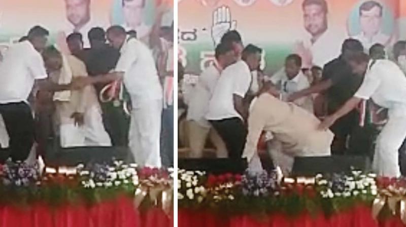 Chief Minister Siddaramaiah slips and falls on the stage at a public meeting at HD Kote in Mysuru on Sunday. His supporters were quick to assist him. 	(Photo:KPN)