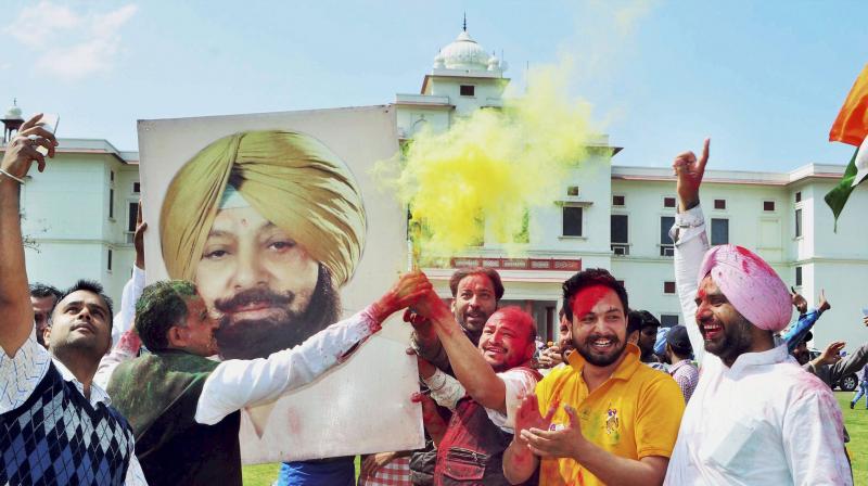 Congress workers celebrate with a poster of PPCC President Capt. Amarinder Singh the partys thumping victory in the State Assembly polls. (Photo: PTI)