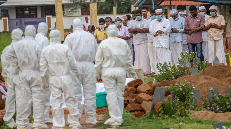 Relatives and hospital officals wear safety masks as they perform the last rites of V Moosa (61), a Nipah virus victim, at Kannam Parambu graveyard, in Kozhikode, on Thursday.