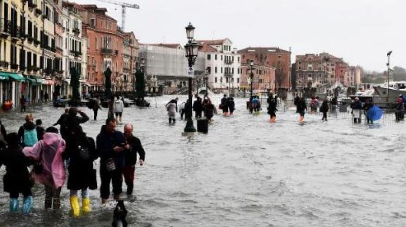 People walk in the flooded street during a high-water alert in Venice. (Photo: AFP)
