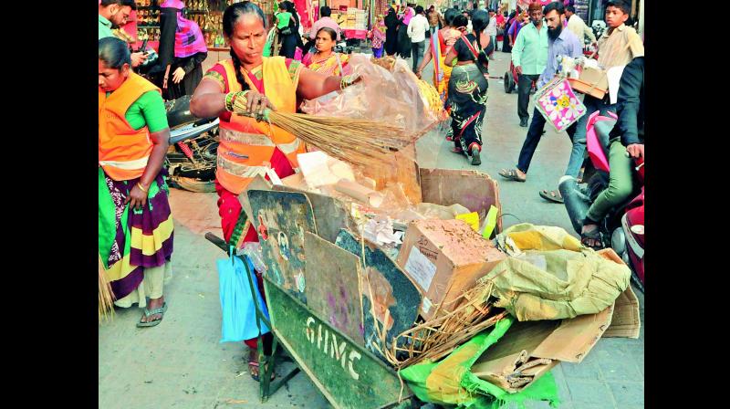 GHMC staff collect garbage from the pavements of Charminar on Tuesday as there are no garbage bins around the monument. (Photo: DC)