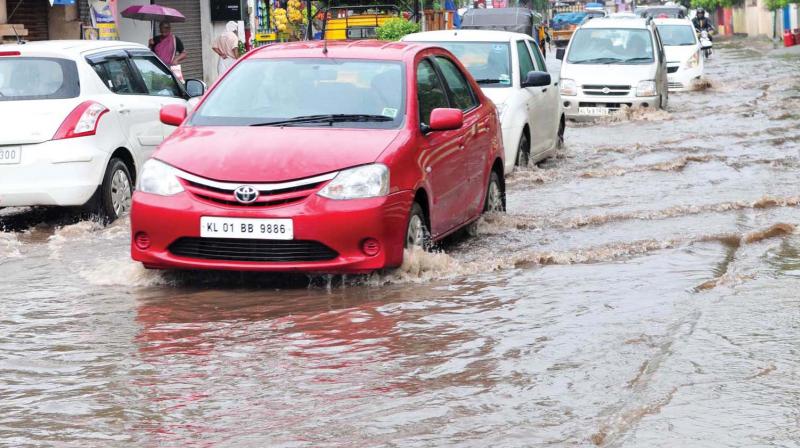 Vehicles wade through the flooded Kamaleshwaram road in Thiruvananthapuram city after the rains on Saturday. (Photo: DC)