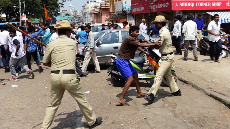 Police personnel in action against the protestors in Shaivajinagar area where an RSS worker was murdered, in Bengaluru. (Photo: PTI)