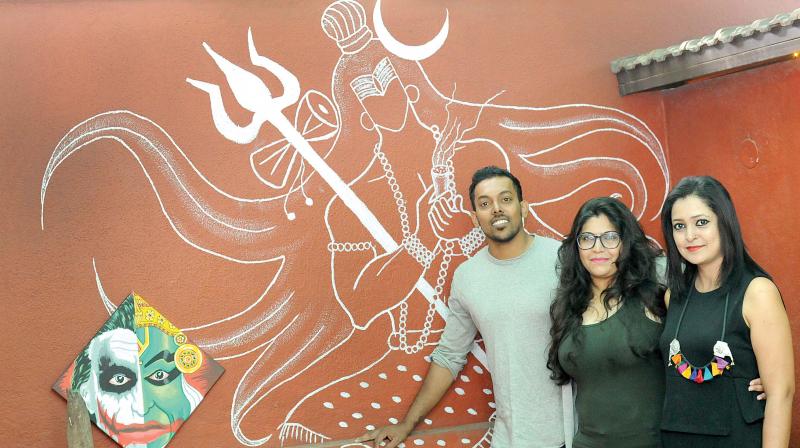 Nithin Chandran, Lakshmi Priya and Rashmi Naren pose in front of a wall they created at a friends garden.