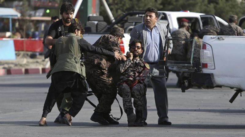 Afghan security personnel carry an injured comrade after an attack near the Kabul International Airport, in Kabul, Afghanistan, Sunday. (Photo: AP)