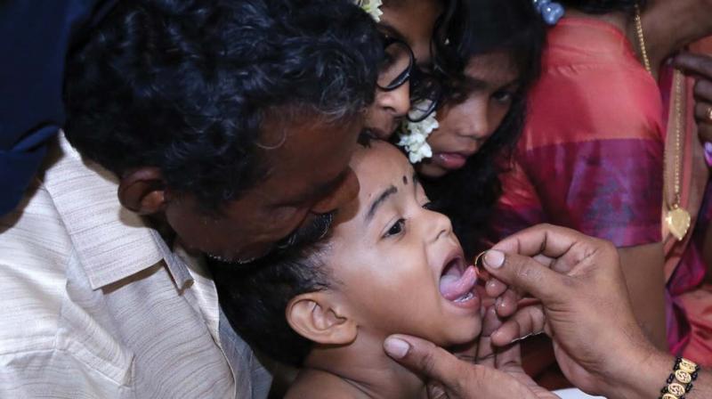Harisree being written on the tongue of a kid using a golden ring during the ezhuthiniruthu ceremony held at Thiruvullakkavu Temple in Thrissur on Friday. 	 	Image: ANUP K VENU