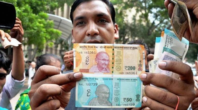 A man shows new Rs 200 and Rs 50 ntes outside RBI in New Delhi. (Photo: PTI)