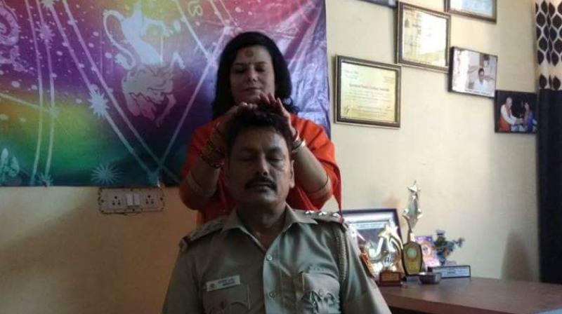 n the viral-picture, the officer is seen in his uniform with his eyes shut as the saffron-robed Namita Acharya, who calls herself a sadhvi, is seen standing behind him in a gesture of blessing. (Photo: Twitter | ANI)