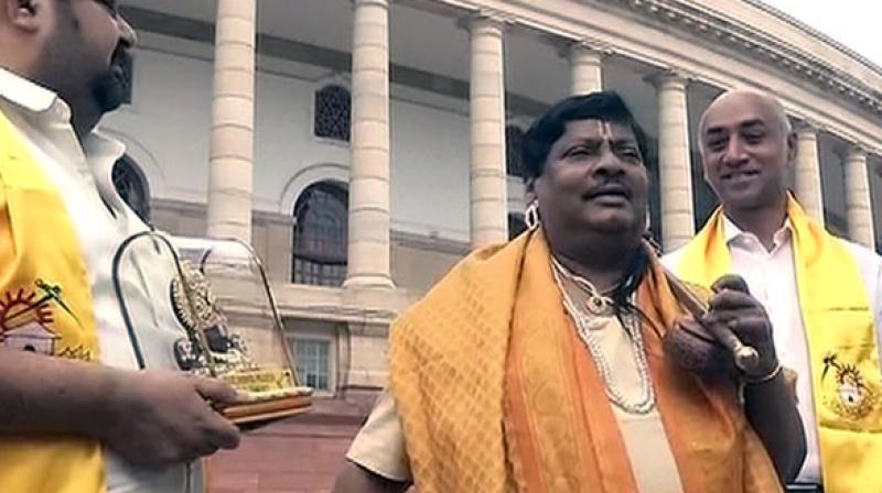 Dressed as Annamayya, Sivaprasad was seen with a gold silk drape around his shoulders, a yellow waist band and was seen holding an iktara, near the Mahatma Gandhi statue in the parliament complex. (Photo: ANI)
