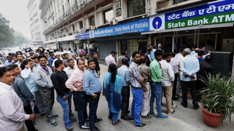 People queue up outside an ATM to withdraw money in New Delhi. (Photo:PTI)