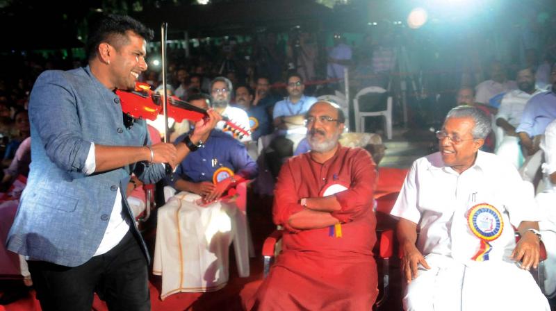 Violinist Balabhaskar performs as Finance Minister T. M. Thomas Isaac and Chief Minister Pinarayi Vijayan look on during the first anniversary celebration of the LDF government at Nishagandhi in Thiruvananthapuram on Thursday . (Photo: A.V. MUZAFAR)