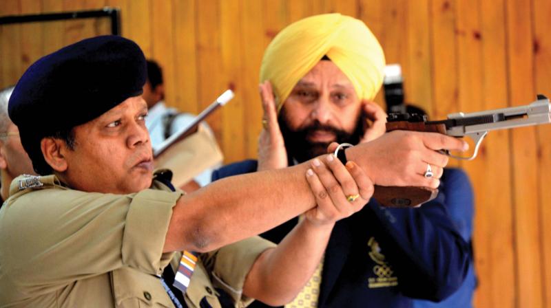 DGP Loknath Behera tries a gun to mark the inauguration of the national police shooting meet at Vattiyoorkavu shooting range in Thiruvananthapuram on Monday. (Photo: PEETHAMBARAN PAYYERI)