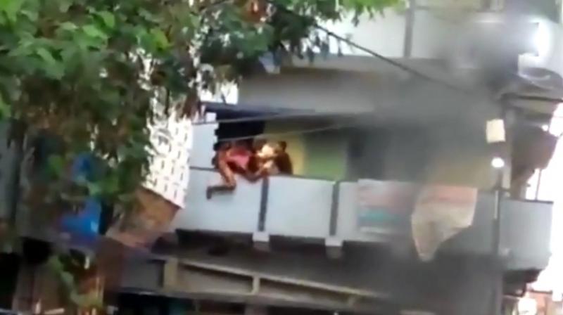 In the video, recorded from the spot of the incident, a group of people were seen holding the man and attempting to push him off the veranda. (Screengrab | ANI)