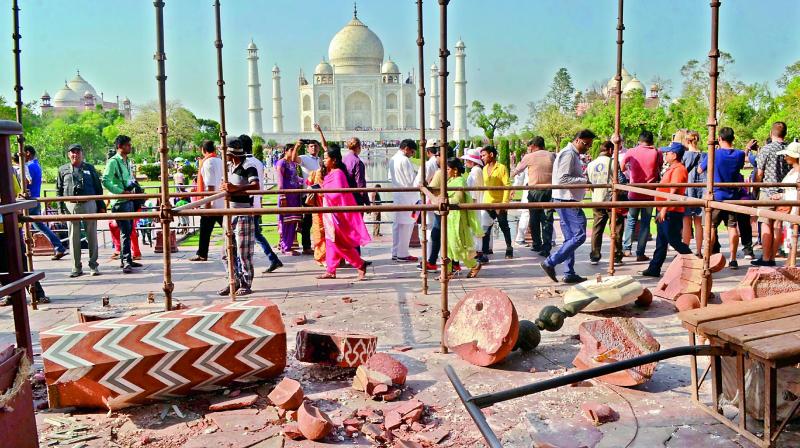 Tourists walk past the debris after a powerful storm Wednesday night toppled two minarets at the entry gates of the Taj Mahal on Thursday.  (Photo: AP )