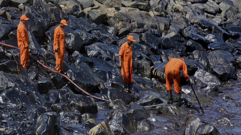 Coast Guard personnel work to clear the slick after an oil spill polluted the Ennore beach on the Bay of Bengal coast near Chennai. (Photo: AP)