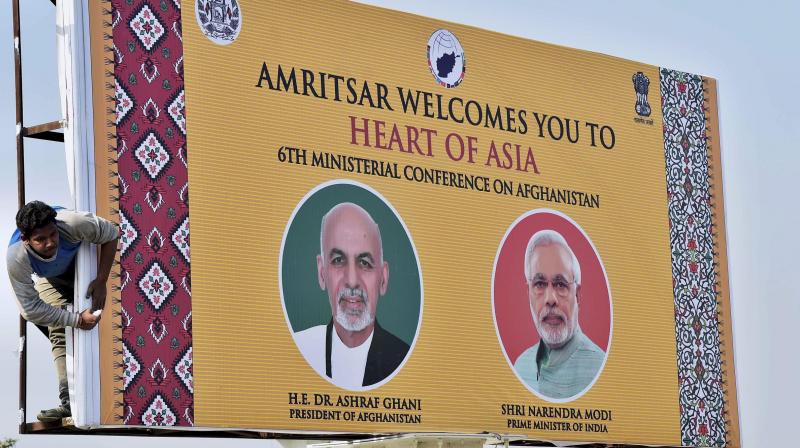 A worker erects a billboard showing pictures of Prime Minister Narendra Modi and Afghan President Ashraf Ghani on a street ahead of the sixth ministerial conference on Afghanistan in Amritsar. (Photo: PTI)