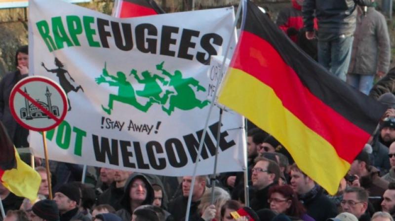 Far-right demonstrators hold a sign â€œRapefugees not welcome  !Stay away!â€and a sign with a crossed out mosque as they march in Cologne, Germany. (Photo: AP)