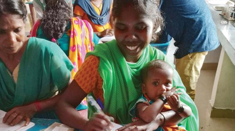 A tribal woman attends the test with her toddler in the lap.