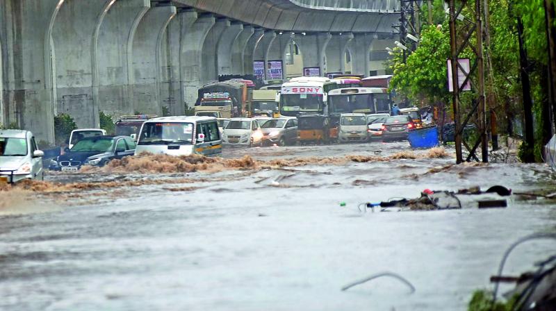 Commuters making their way through flooded streets early in the morning in Uppal as heavy rains pounded the city on Thursday.  (Photo: Gandhi)