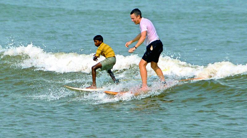 A foreigner enjoy surfing along with a local boy at Rushikonda Beach in Visakhapatnam.