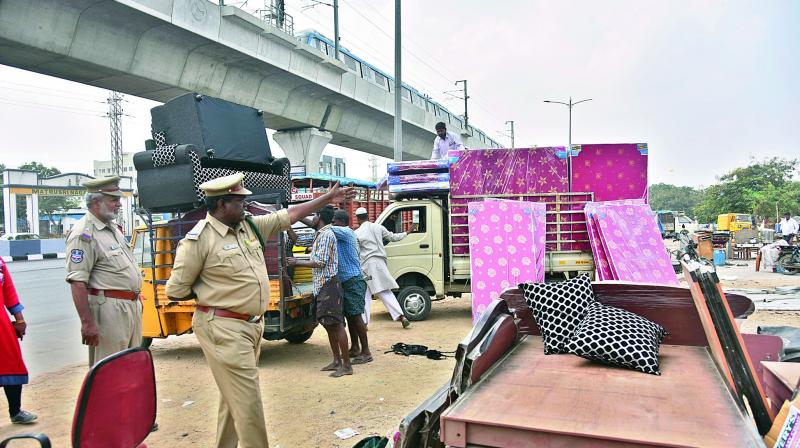 Cops remove the encroachments near  Miyapur Metro station before the inauguration. Trial runs of the Metro seen in the backdrop. (Photo: DC)