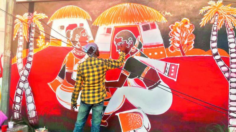 An artist works on a paiting on one of the landmark sites in the city on Saturday, that are being readied for the upcoming World Telugu Conference.