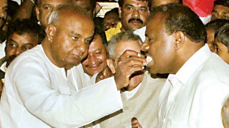 JD(S) supremo H.D. Deve Gowda offers a slice of cake to his son and partys state chief H.D. Kumaswamy on his 59th birthday in Bengaluru Saturday (Photo: DC)