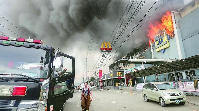 A firefighter stands in front of the burning shopping mall in Davao City on the southern Philippine island of Mindanao on Sunday. (Photo: AFP)