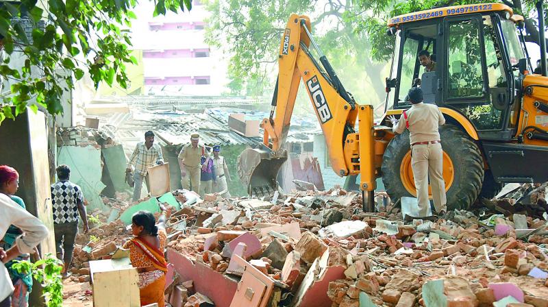 An earthmover demolishes slums in East Marredpally. The slumdwellers have given up the land to be redeveloped with 2BHK houses. (Photo: DC)