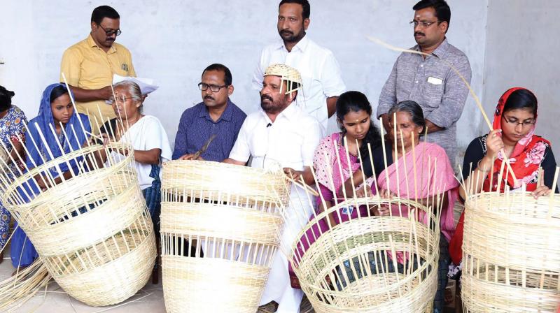 Thrissur DCC president T.N. Prathapan joins weavers of bamboo waste bins, to be used for State School Youth Festival, at Mangad RCPL School on Thursday. Since the festival has to adhere to the green protocol, such eco-friendly bins will be used at all venues. (Photo: ANUP K. VENU)