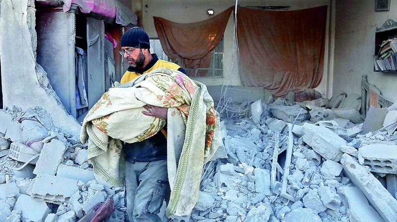 A member of the Syrian civil defence carries the body of a child out of a rubble in a house that was hit by a air strike in the rebel-held town of Jisreen. (Photo:AFP)