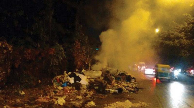 Toxic fumes rise from a heap of garbage burning at third cross in Kasturi Nagar.  (Photo:DC)