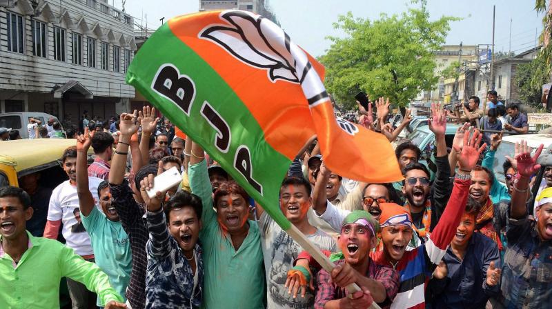 BJP supporters wave party flag to celebrate BJPs win, which brought down 25 years of CPI-M government rule, after Tripura Assembly election results were announced in Agartala on Saturday. (Photo: PTI)