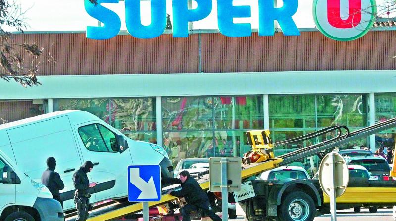 Policemen at work as a van is taken away outside the  Super U supermarket after special forces killed a gunman who had taken several people hostages for more than three hours. 	 (Photo:AFP)