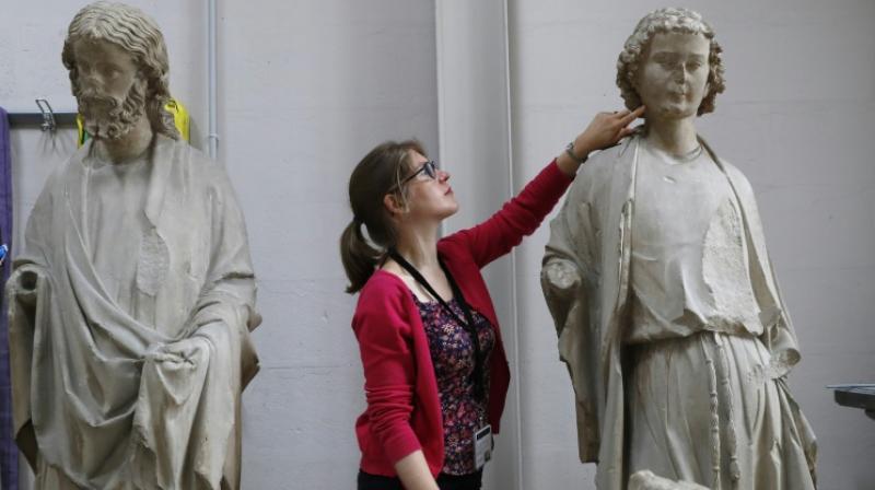 Heritage Curator of the Centre for Research and Restoration of Museums of France (C2RMF) Alexandre G©rard examines polychrome stone statues belonging to the Museum of Cluny, the \apostles of the Sainte Chapelle\ before their restoration in Paris. (Photo: AFP)