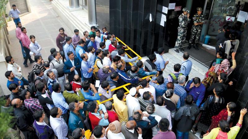People wait outside a bank in New Delhi on Saturday (Photo: AP)