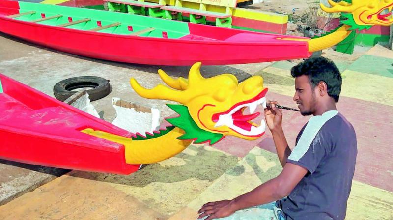 A participant gives final touches to a dragon boat ahead of the boat race, at Avanigadda in Krishna district on Wednesday.