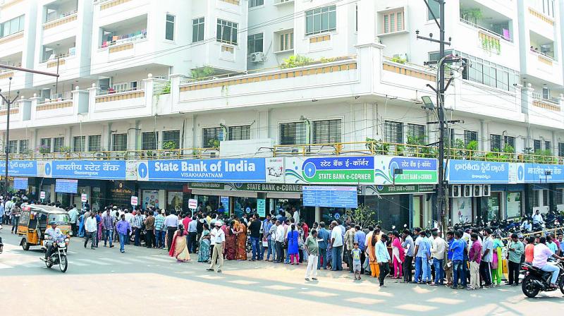 People wait in a large queue outside a bank to exchange the demonitised Rs 500 and Rs 1,000 currency notes outside the SBI main branch in Visakhapatnam on Saturday.