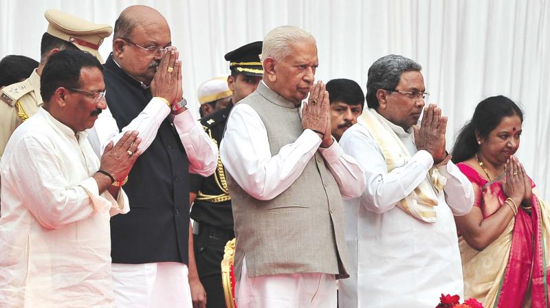 Governor Vajubhai Vala, CM Siddaramaiah and the three newly inducted ministers R.B. Thimmapur, H.M. Revanna and Geetha Mahadevprasad at the swearing-in ceremony at Raj Bhavan on Friday