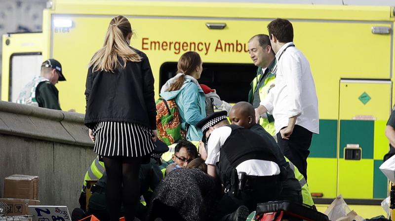 Emergency services staff provide medical attention close to the Houses of Parliament in London. (Photo: AP)