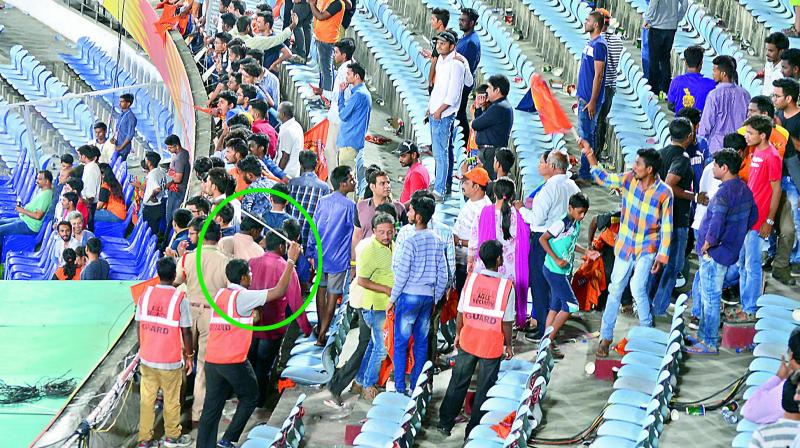 A guard (circled) from the Agile Security services tries to charge spectators at the South Pavilion East enclosure as he drives them out even as they watch the post-match presentation ceremony of the Sunrisers vs Kolkata Knight Riders match at the Rajiv Gandhi International Cricket Stadium in Hyderabad on Saturday.