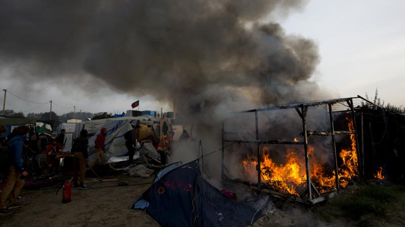 Firefighters work extinguishing burning tents in a makeshift migrant camp known as the jungle near Calais, northern France, on Wednesday. (Photo: AP)